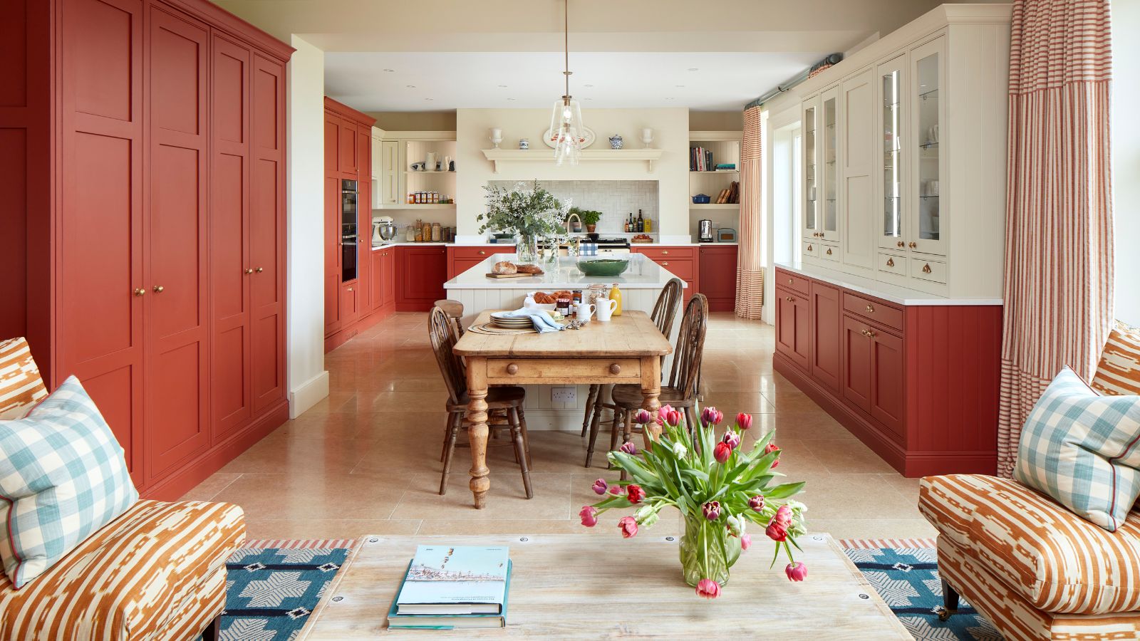 An open plan kitchen and living area with red cabinets and a blue rug beneath the seating area to create zones