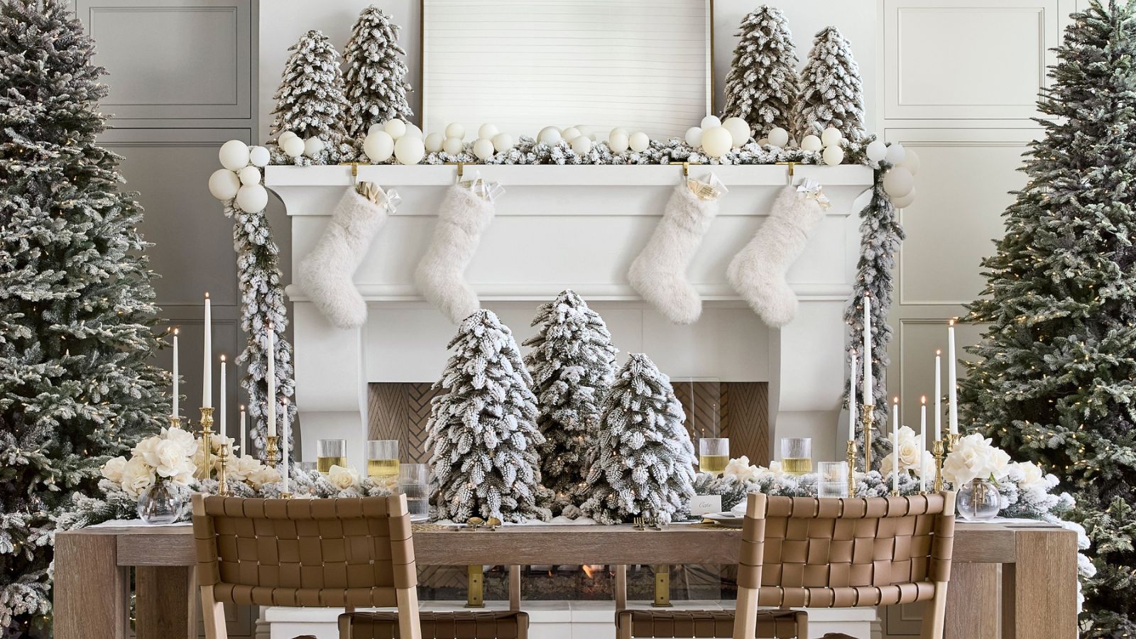 Small and large frosted faux Christmas trees in front of a white festive mantel