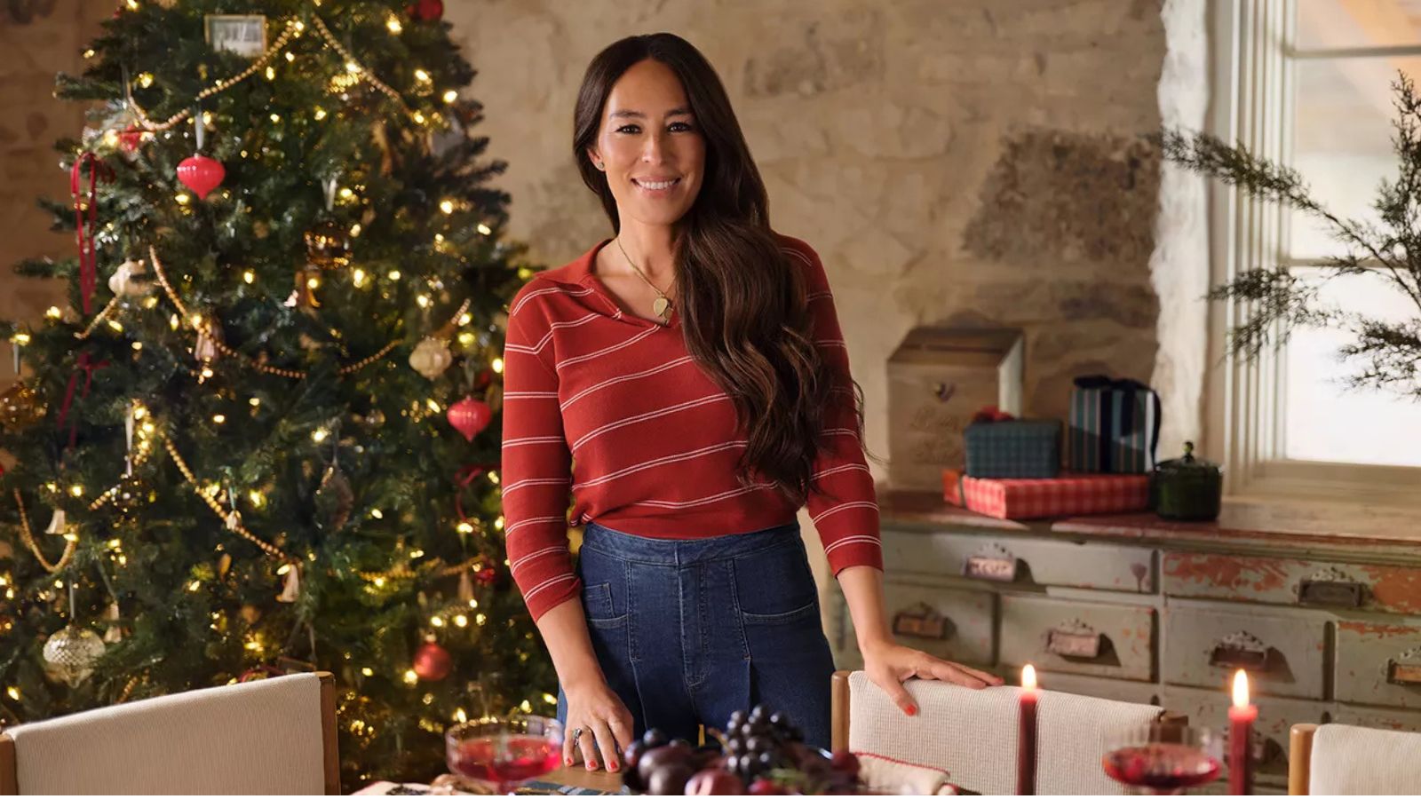 Joanna Gaines in dining room with a christmas tree and antique drawers in background