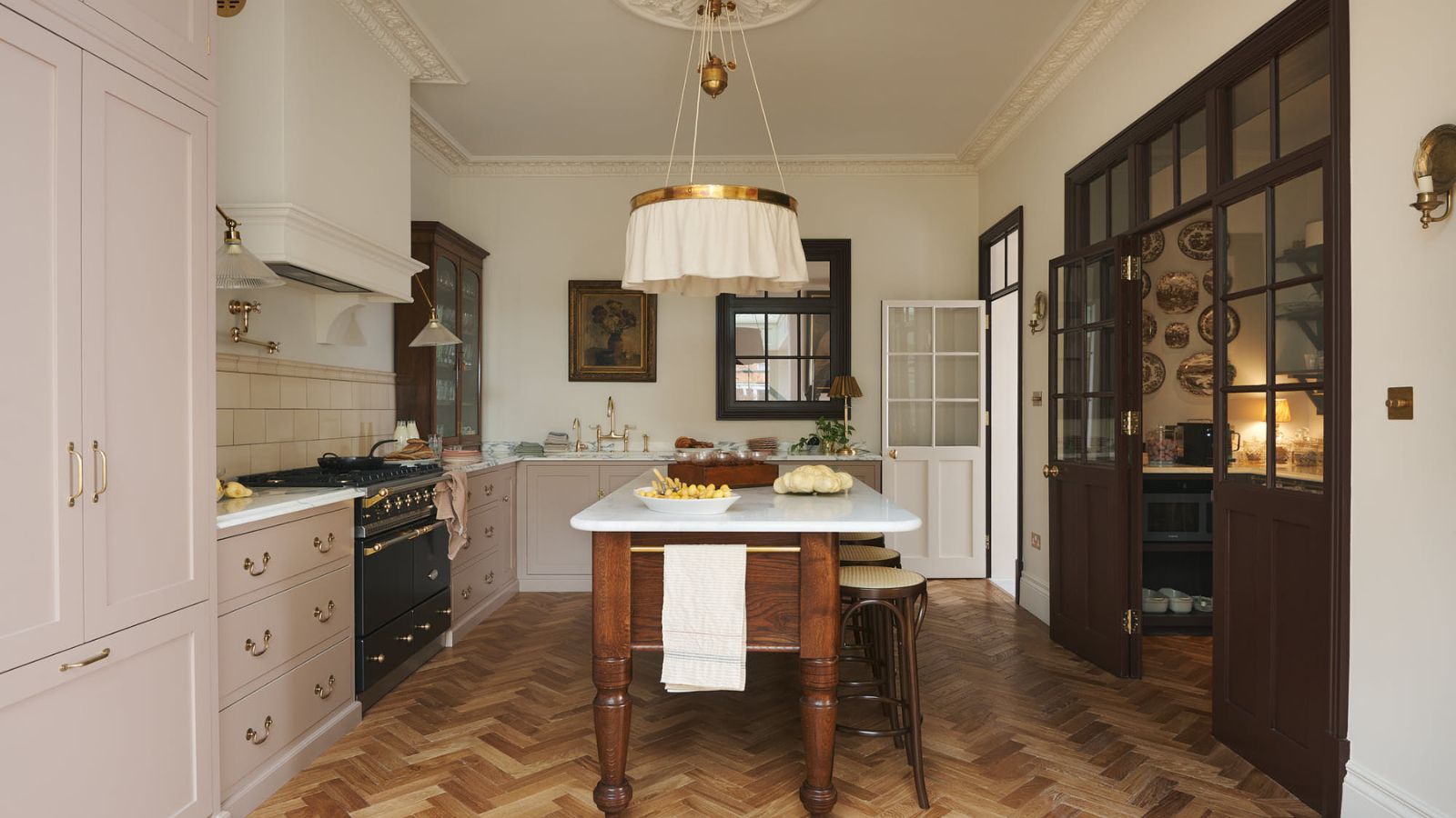 A large pink and white kitchen with a pantry connected by wood and glass doors
