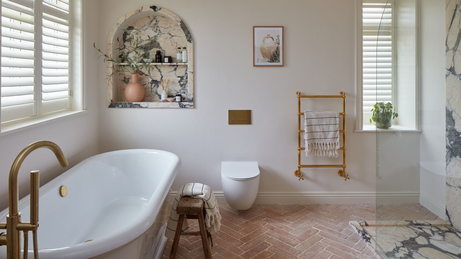A white and marble bathroom with terracotta floor tiles