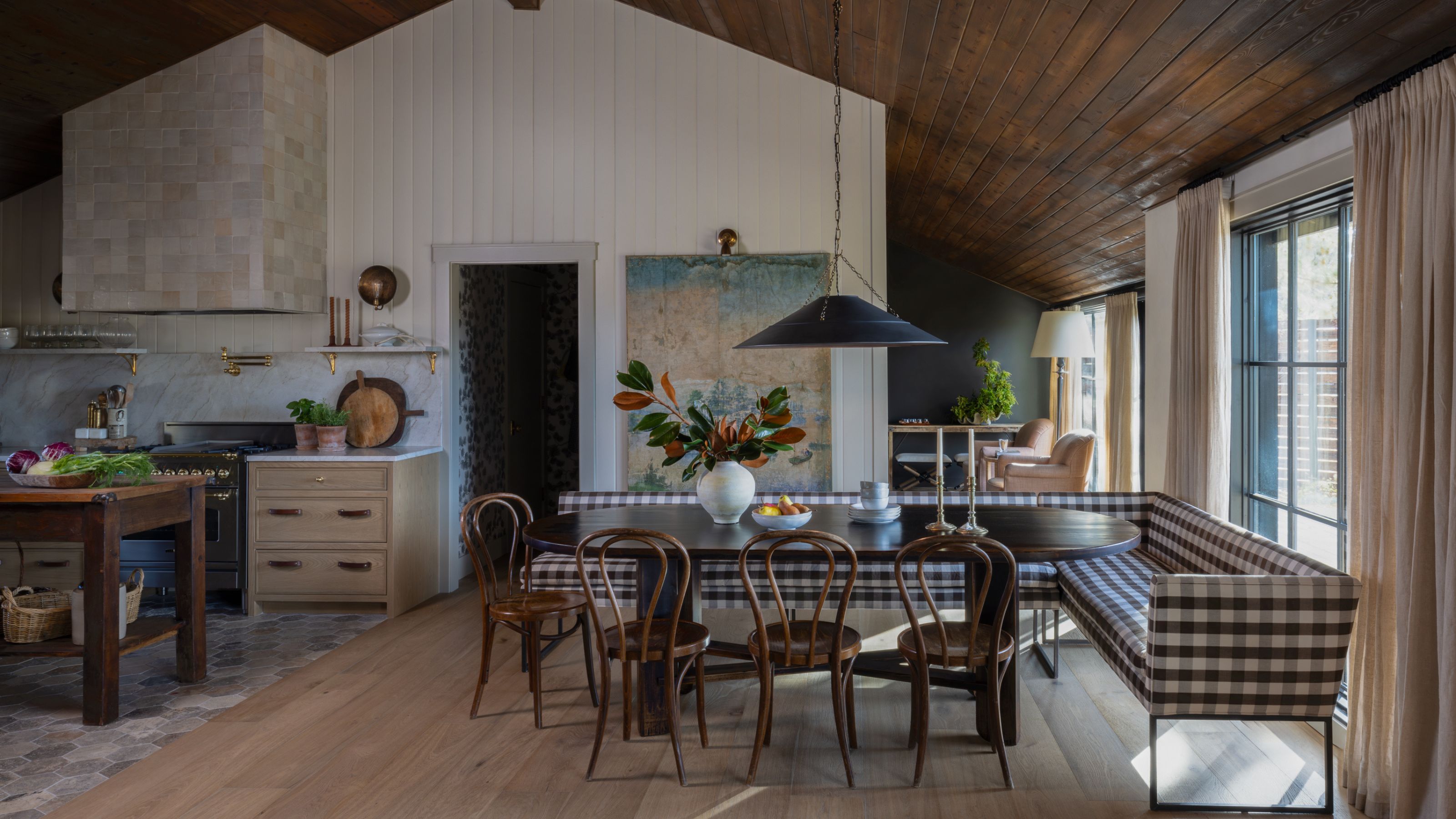 Open concept kitchen diner with a banquette dining space with gingham upholstered seating