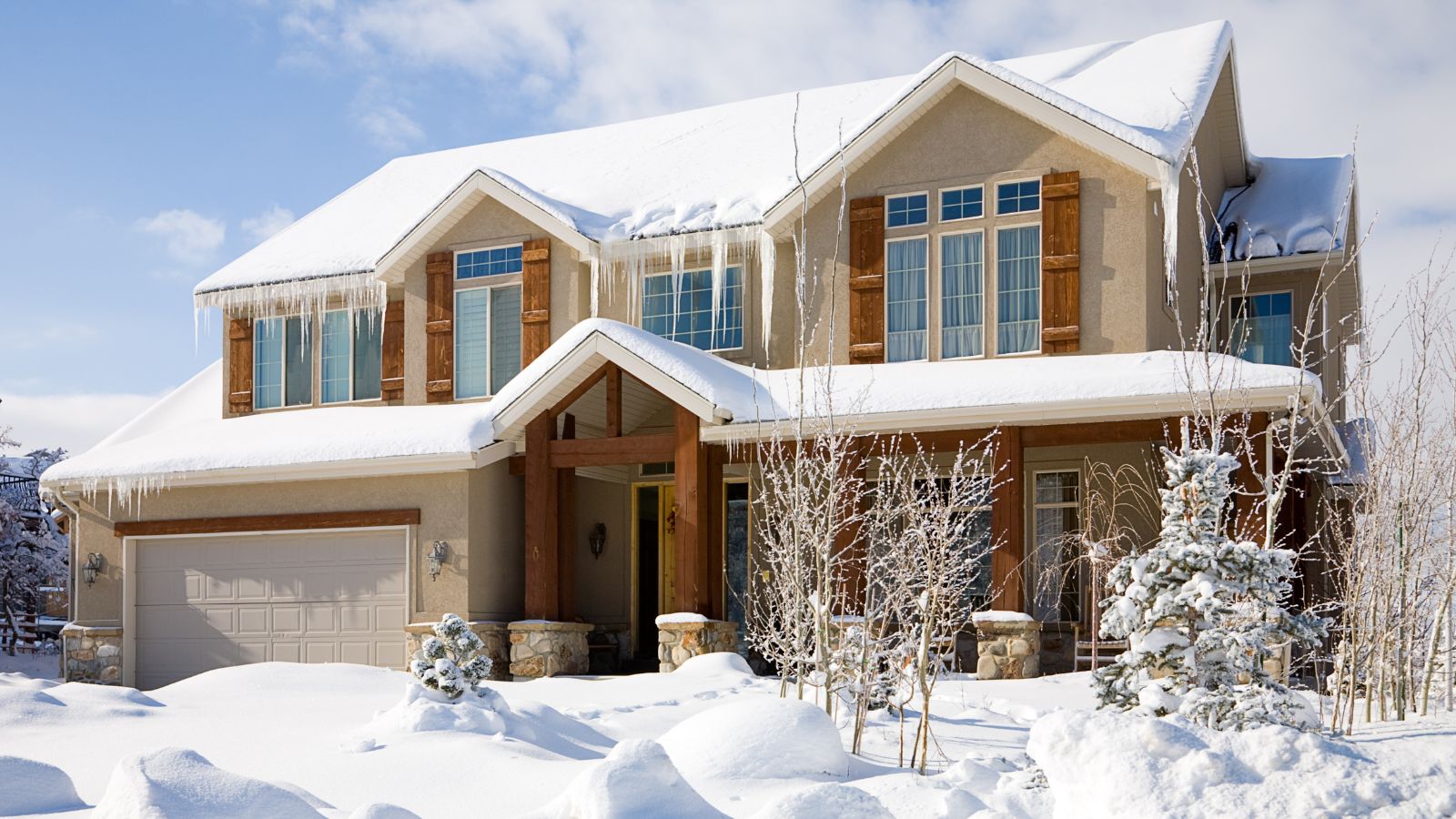 A snow covered luxury home under blue sky 