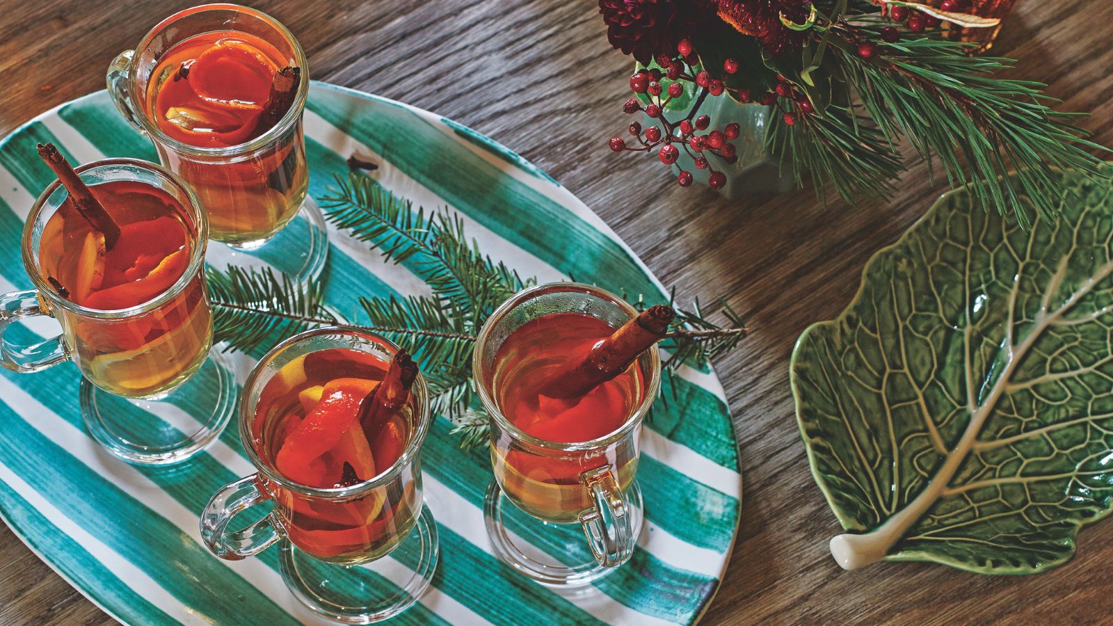 Glasses of hot toddy on a green and white plate with festive foliage