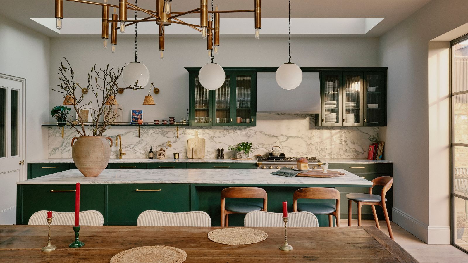 A family kitchen in an Edwardian home with green cabinets, marble countertops, and wooden accents