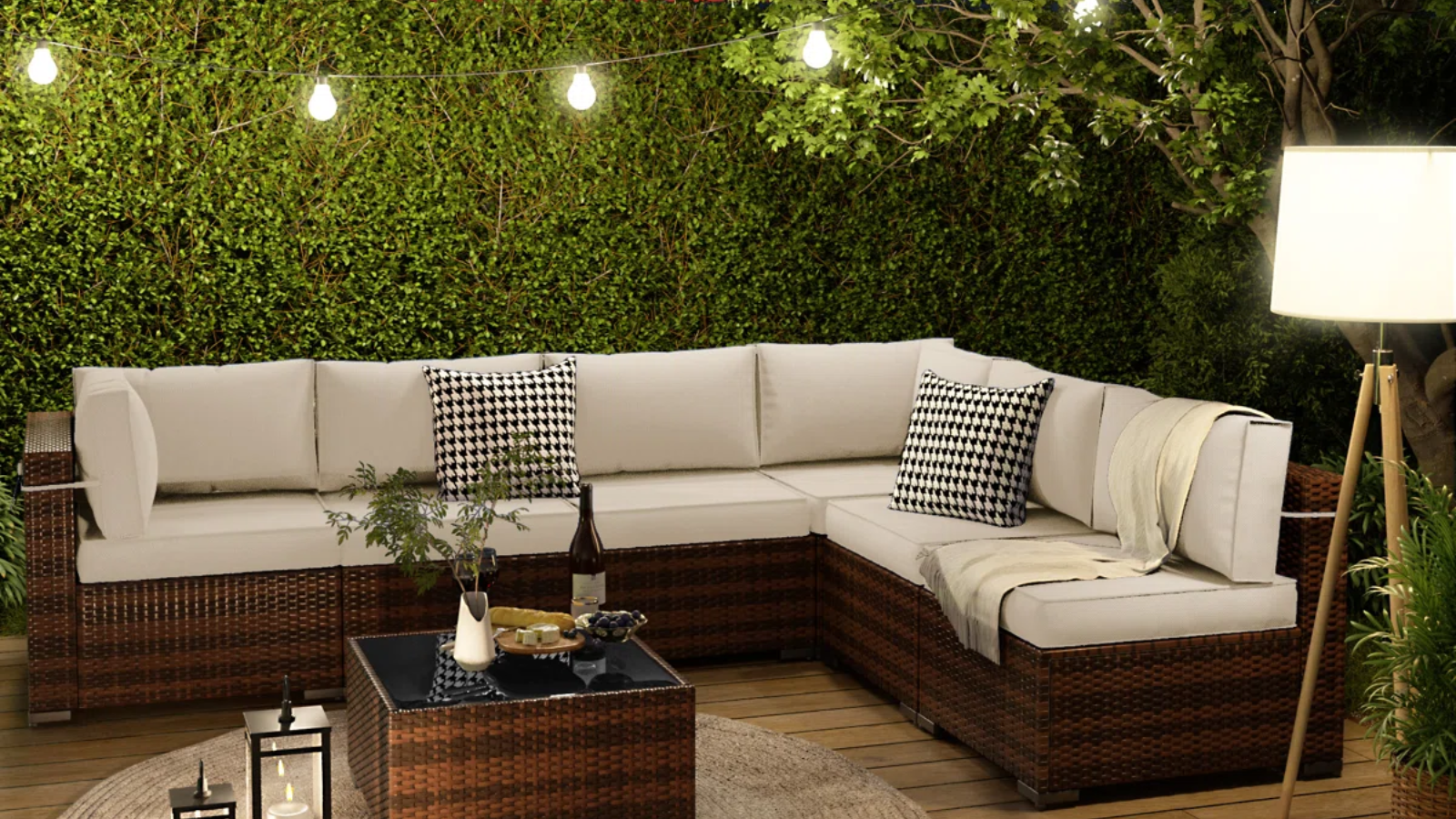 an outdoor seating area with a large sofa, a coffee table, a floor lamp, and string lights