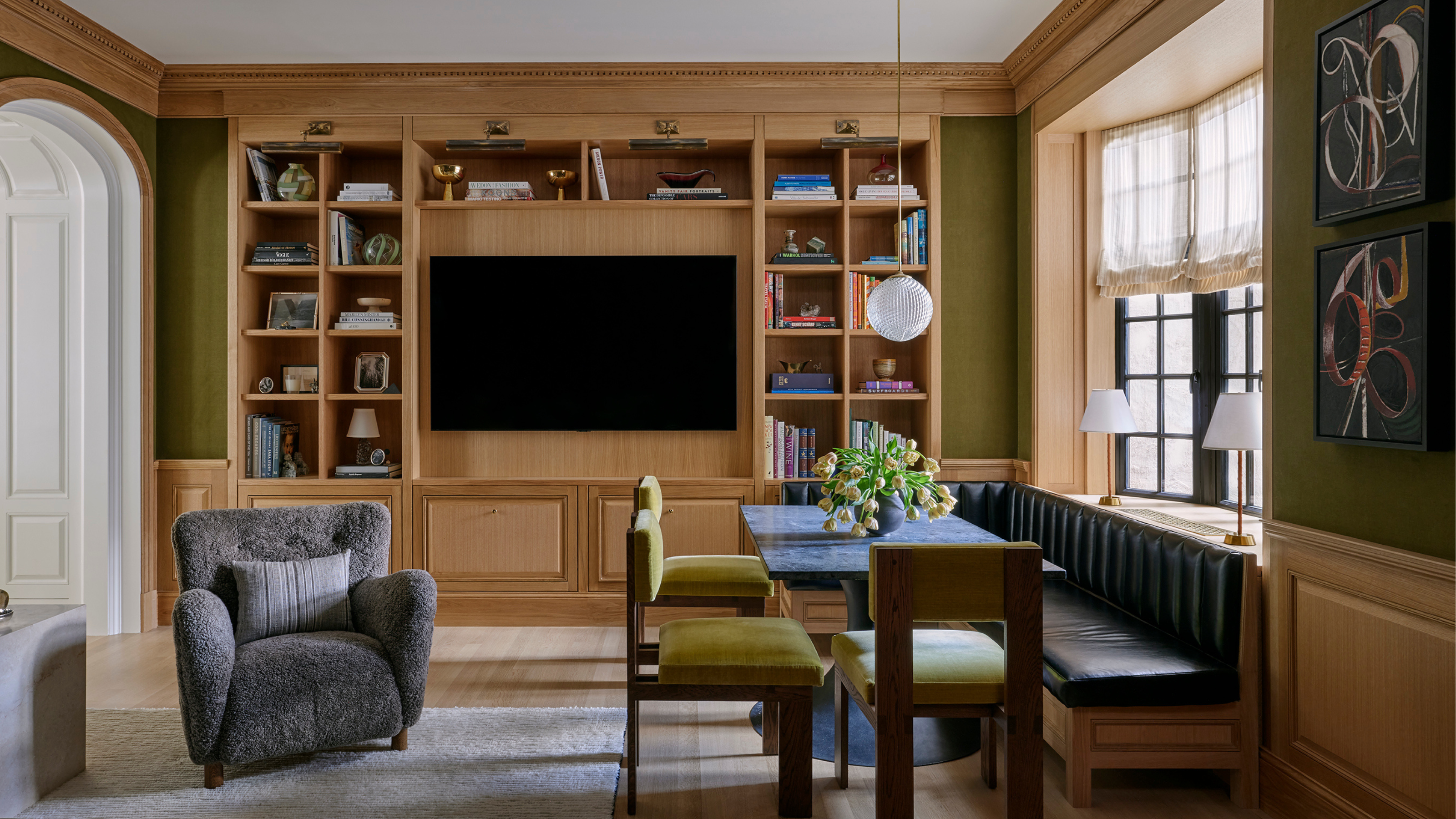 A reimagined formal dining room is now a relaxed family room with a built-in breakfast nook, a wooden bookshelf, and eclectic furnishing.